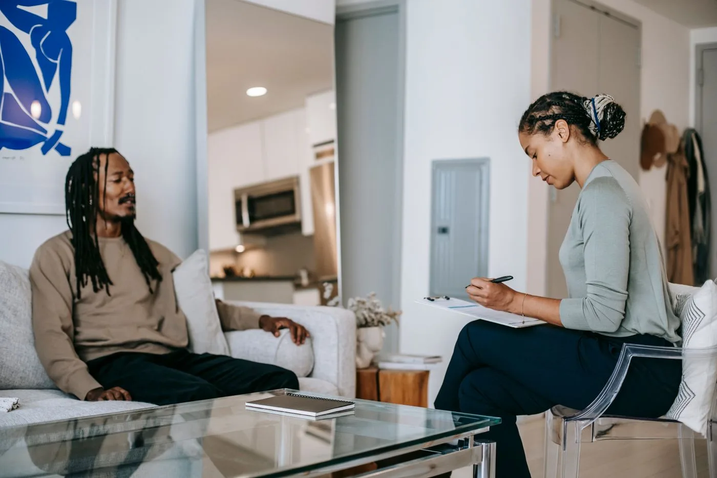 A therapist taking notes during a session with a client in a bright, calm room